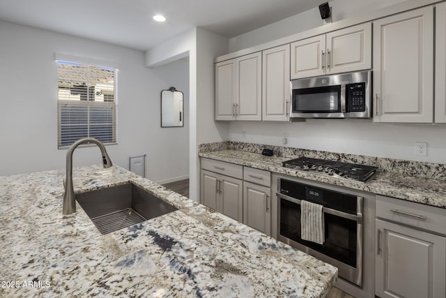 kitchen with sink, dark wood-type flooring, stainless steel appliances, and light stone countertops