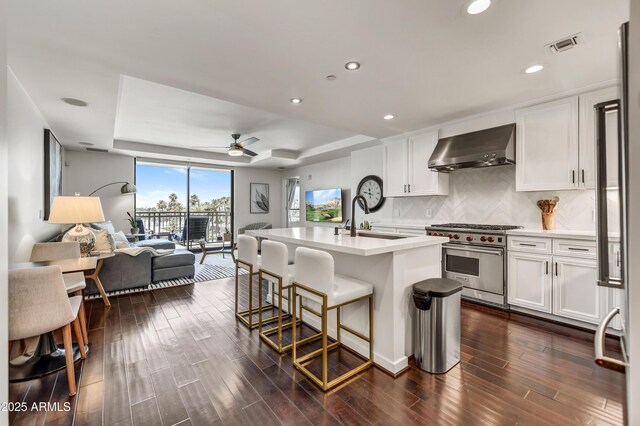 6803 E Main St Unit 5506, Scottsdale, AZ 85251 - kitchen featuring premium stove, wall chimney exhaust hood, open floor plan, a ceiling fan, and decorative backsplash