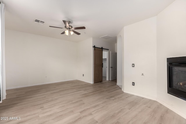 1162 S Agnes Ln, Gilbert, AZ 85296 - unfurnished living room with light wood-style floors, a ceiling fan, baseboards, and a barn door