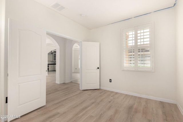 1162 S Agnes Ln, Gilbert, AZ 85296 - spare room featuring light wood finished floors, baseboards, and arched walkways