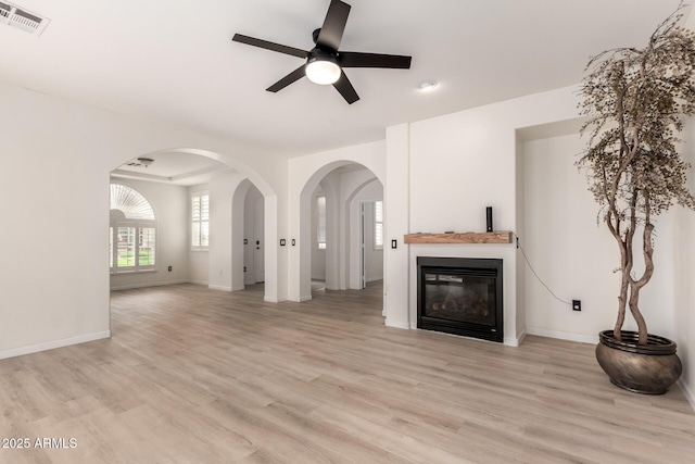 1162 S Agnes Ln, Gilbert, AZ 85296 - unfurnished living room with ceiling fan, light wood-style floors, a glass covered fireplace, and baseboards
