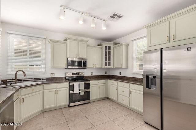 1162 S Agnes Ln, Gilbert, AZ 85296 - kitchen featuring stainless steel appliances, a sink, cream cabinets, dark countertops, and light tile patterned floors