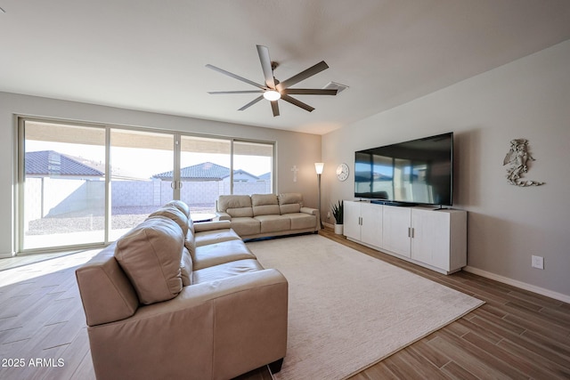 living area with a ceiling fan, visible vents, baseboards, and wood finished floors