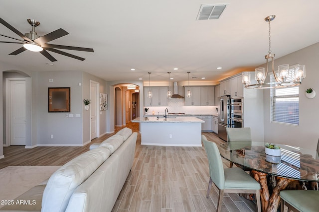 dining space featuring baseboards, visible vents, arched walkways, light wood-style floors, and recessed lighting