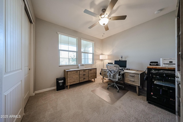 home office with baseboards, a ceiling fan, and light colored carpet