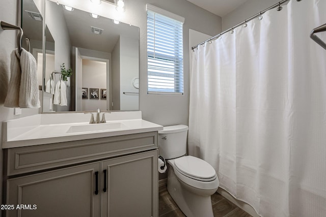 bathroom featuring visible vents, a shower with shower curtain, toilet, wood finished floors, and vanity