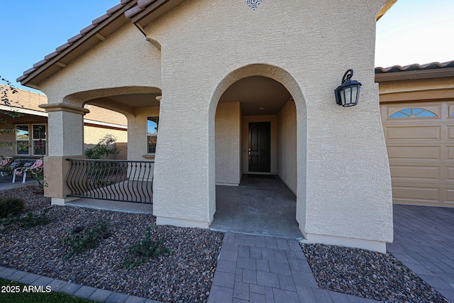 property entrance featuring covered porch, a tile roof, and stucco siding