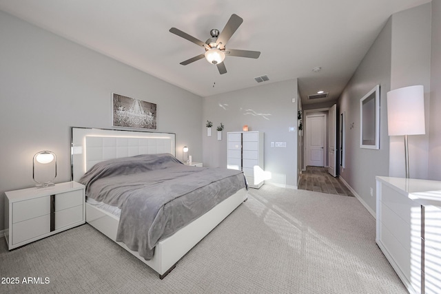 bedroom with light carpet, a ceiling fan, visible vents, and baseboards