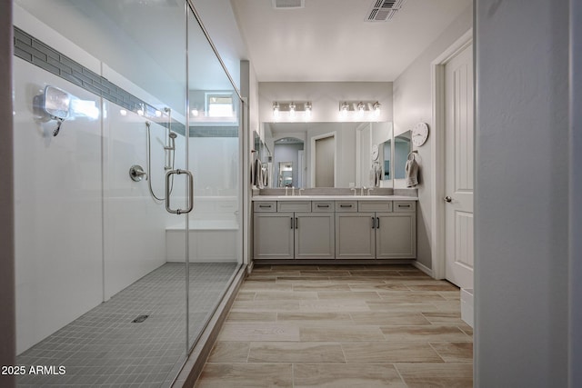 bathroom featuring double vanity, a stall shower, visible vents, and a sink