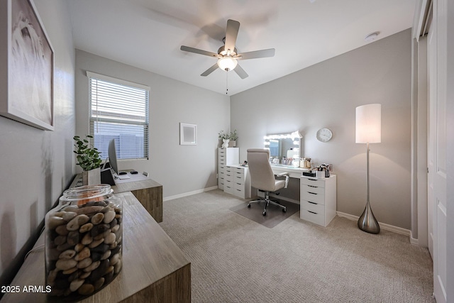 office space featuring light carpet, a ceiling fan, and baseboards