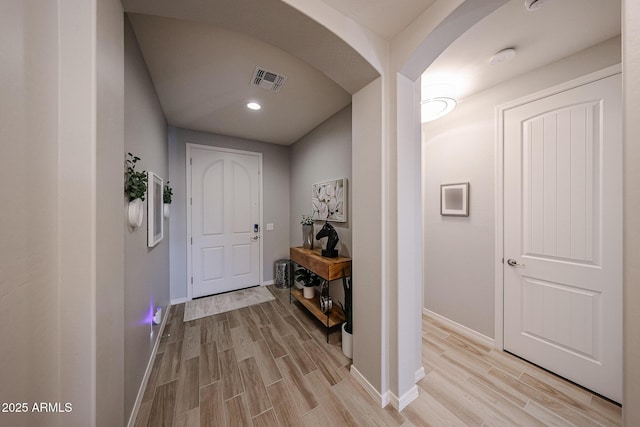 interior space with wood tiled floor, visible vents, arched walkways, and baseboards