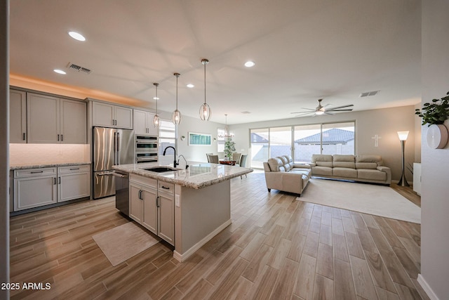 kitchen with appliances with stainless steel finishes, wood finish floors, visible vents, and a sink