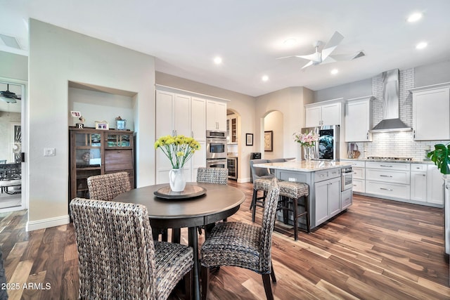 kitchen with white cabinetry, ceiling fan, wall chimney exhaust hood, and a kitchen island