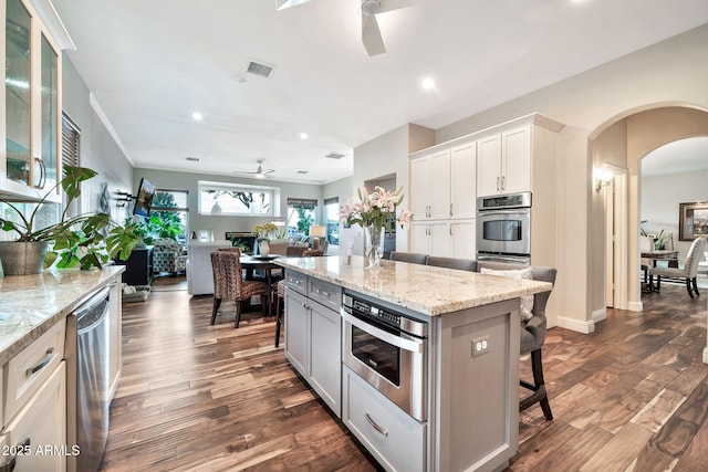 kitchen with ceiling fan, appliances with stainless steel finishes, a kitchen breakfast bar, a center island, and white cabinets