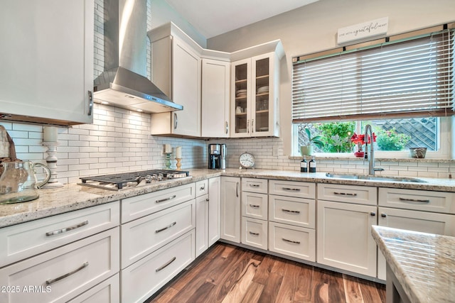 kitchen with white cabinetry, wall chimney range hood, sink, and stainless steel gas stovetop