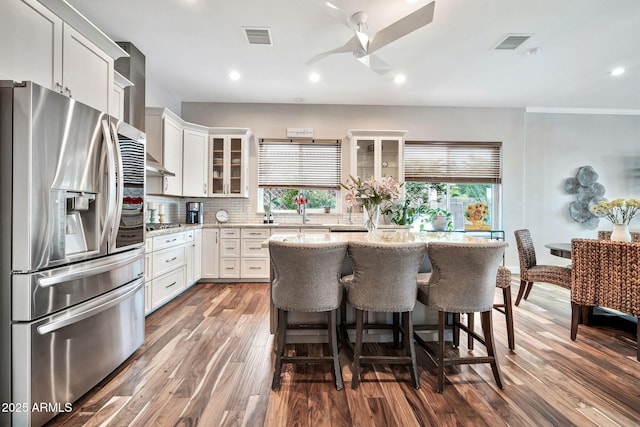 kitchen featuring stainless steel appliances, white cabinetry, light stone countertops, and a center island