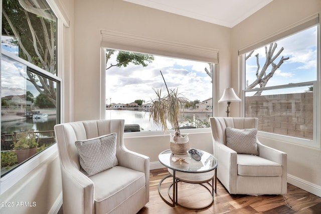 living area featuring a water view, wood-type flooring, and crown molding