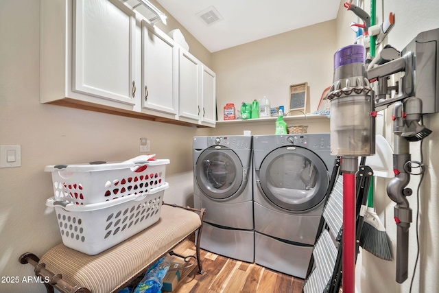 laundry area with washer and dryer, hardwood / wood-style flooring, and cabinets