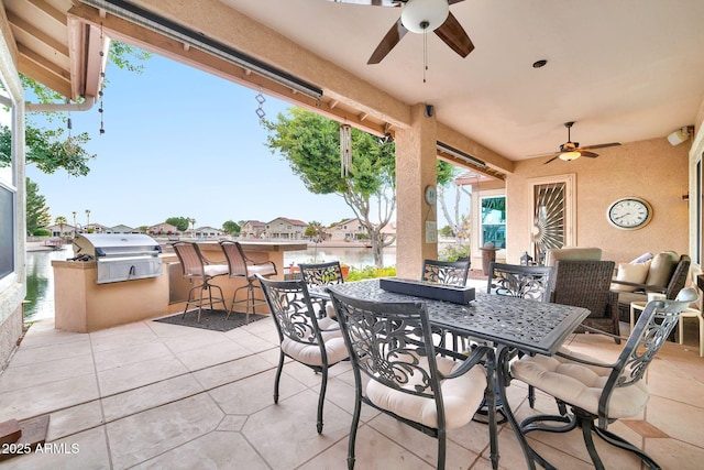 view of patio featuring a bar, area for grilling, ceiling fan, grilling area, and a water view