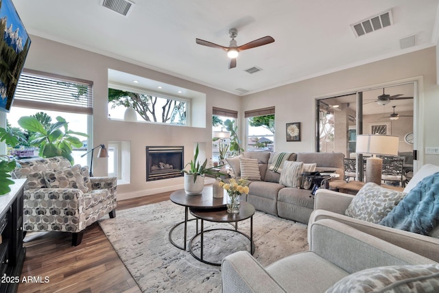 living room with wood-type flooring, ornamental molding, and ceiling fan