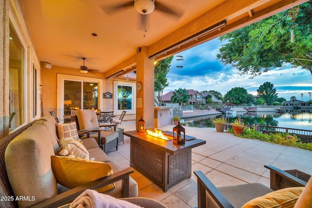 view of patio / terrace featuring a water view, an outdoor living space with a fire pit, and ceiling fan