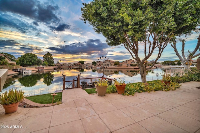 patio terrace at dusk featuring a water view