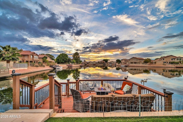 deck at dusk featuring a fire pit and a water view