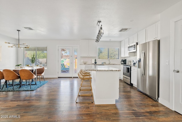 kitchen featuring a healthy amount of sunlight, stainless steel appliances, white cabinets, and a kitchen island