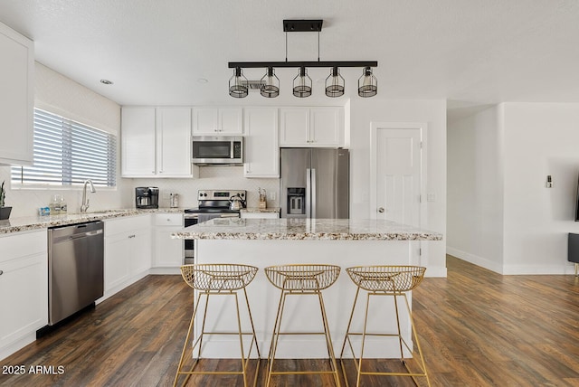 kitchen featuring decorative light fixtures, stainless steel appliances, and a center island