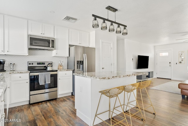 kitchen featuring white cabinetry, decorative light fixtures, tasteful backsplash, and appliances with stainless steel finishes