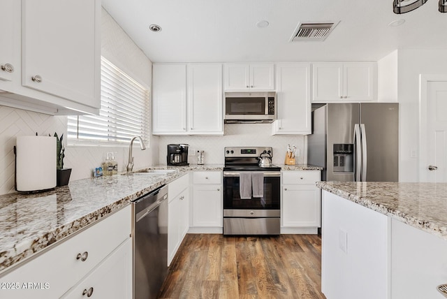 kitchen featuring dark wood-type flooring, sink, light stone counters, appliances with stainless steel finishes, and white cabinets