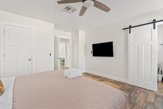 bedroom featuring ceiling fan, a barn door, and hardwood / wood-style floors