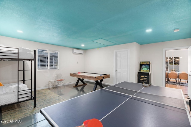 recreation room featuring a wall mounted air conditioner, a textured ceiling, and concrete floors