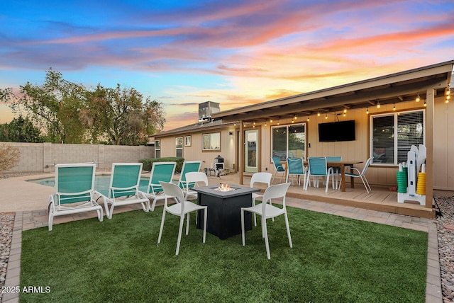 rear view of property with a lawn, a patio, and an outdoor fire pit