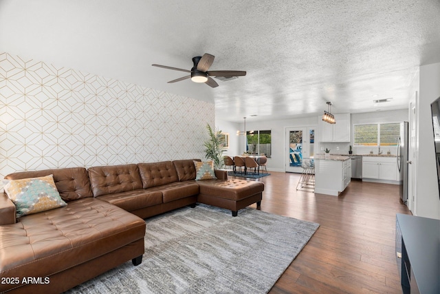 living room featuring ceiling fan, dark hardwood / wood-style flooring, sink, and a textured ceiling