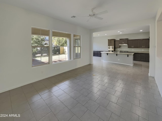 unfurnished living room featuring light tile patterned floors and ceiling fan