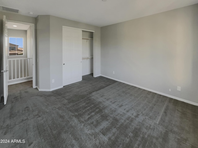 unfurnished bedroom with dark carpet and a closet