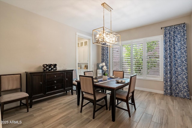 dining room with light wood-style floors, a chandelier, and baseboards
