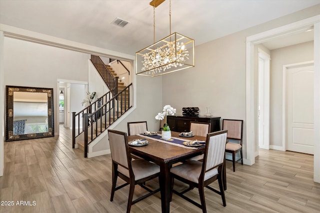dining area with baseboards, light wood-type flooring, visible vents, stairway, and a notable chandelier