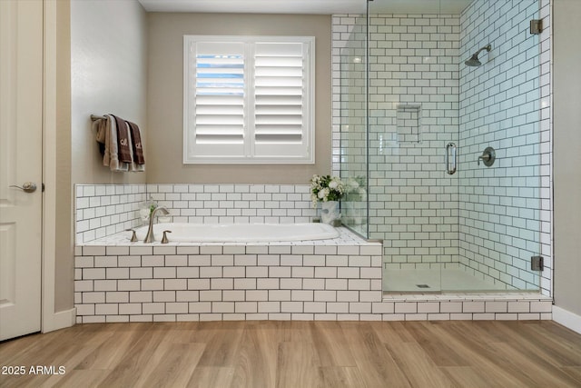 bathroom with a garden tub, wood finished floors, and a stall shower