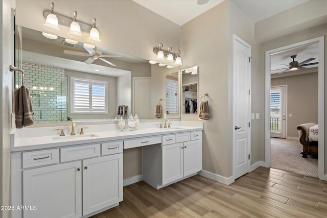 full bathroom with a ceiling fan, a healthy amount of sunlight, a sink, and wood finished floors