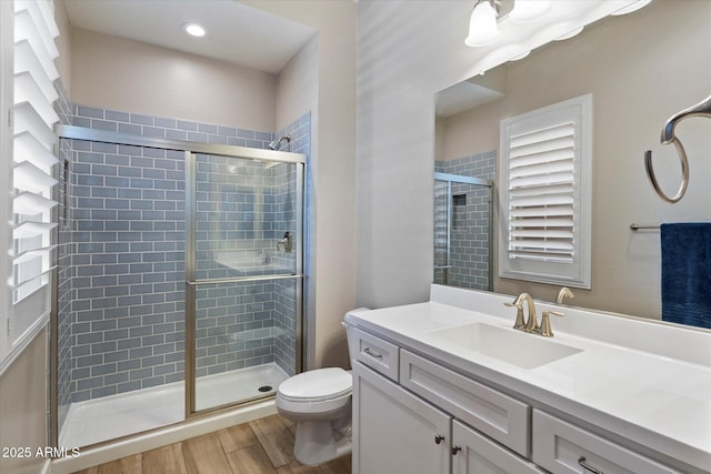 full bath featuring a stall shower, vanity, toilet, and wood finished floors