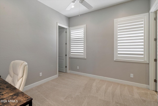 carpeted office featuring baseboards and a ceiling fan