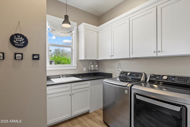 laundry area with a sink, light wood-style flooring, cabinet space, and independent washer and dryer