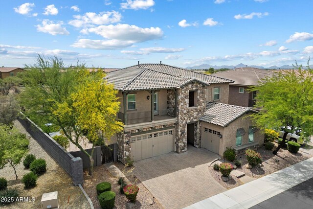 view of front of home featuring stone siding, a garage, a tiled roof, stucco siding, and decorative driveway