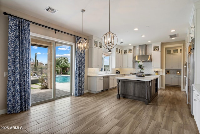kitchen featuring dishwasher, an inviting chandelier, visible vents, wall chimney exhaust hood, and light countertops