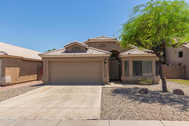 8569 W Voltaire Ave, Peoria, AZ 85381 - mediterranean / spanish-style home with concrete driveway, an attached garage, stucco siding, a tile roof, and fence