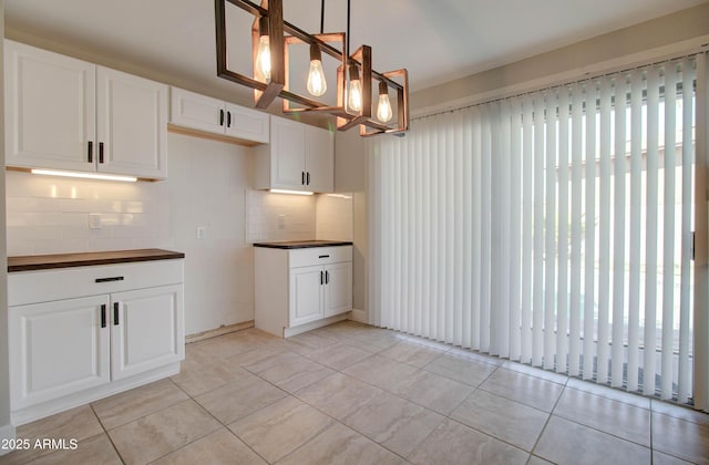 kitchen with light tile patterned floors, hanging light fixtures, white cabinets, and a healthy amount of sunlight