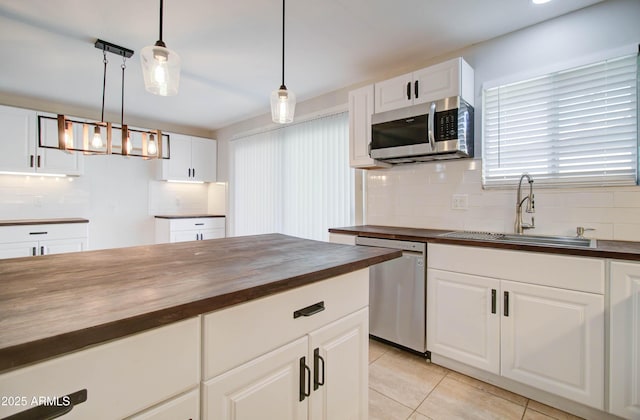 kitchen with wooden counters, sink, white cabinetry, hanging light fixtures, and appliances with stainless steel finishes