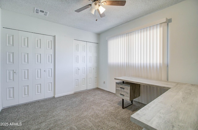 unfurnished office with carpet floors, a textured ceiling, and ceiling fan